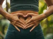 Female torso with hands placed in a heart shape over stomach. Implies she has a healthy gut.