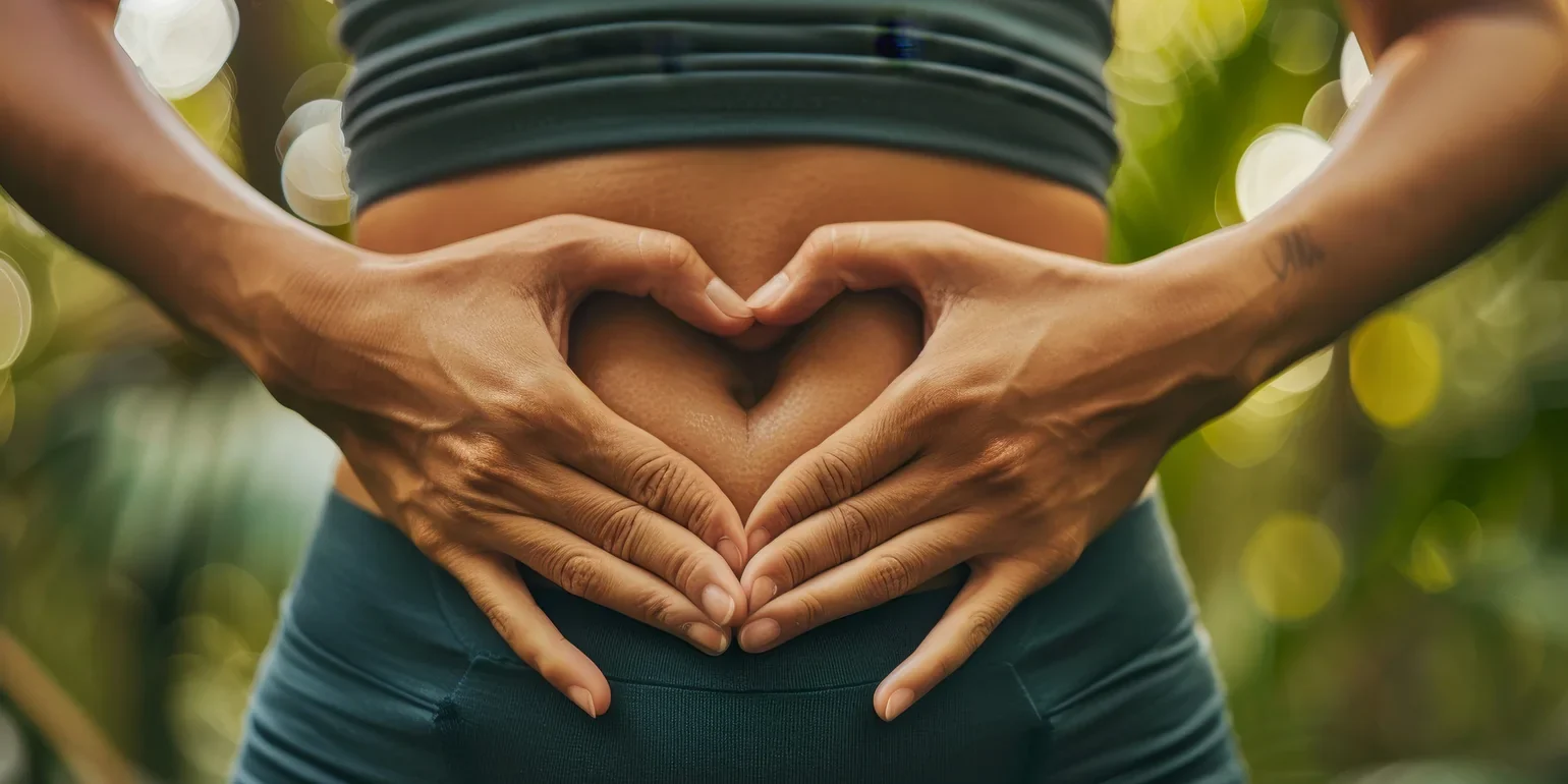 Female torso with hands placed in a heart shape over stomach. Implies she has a healthy gut.