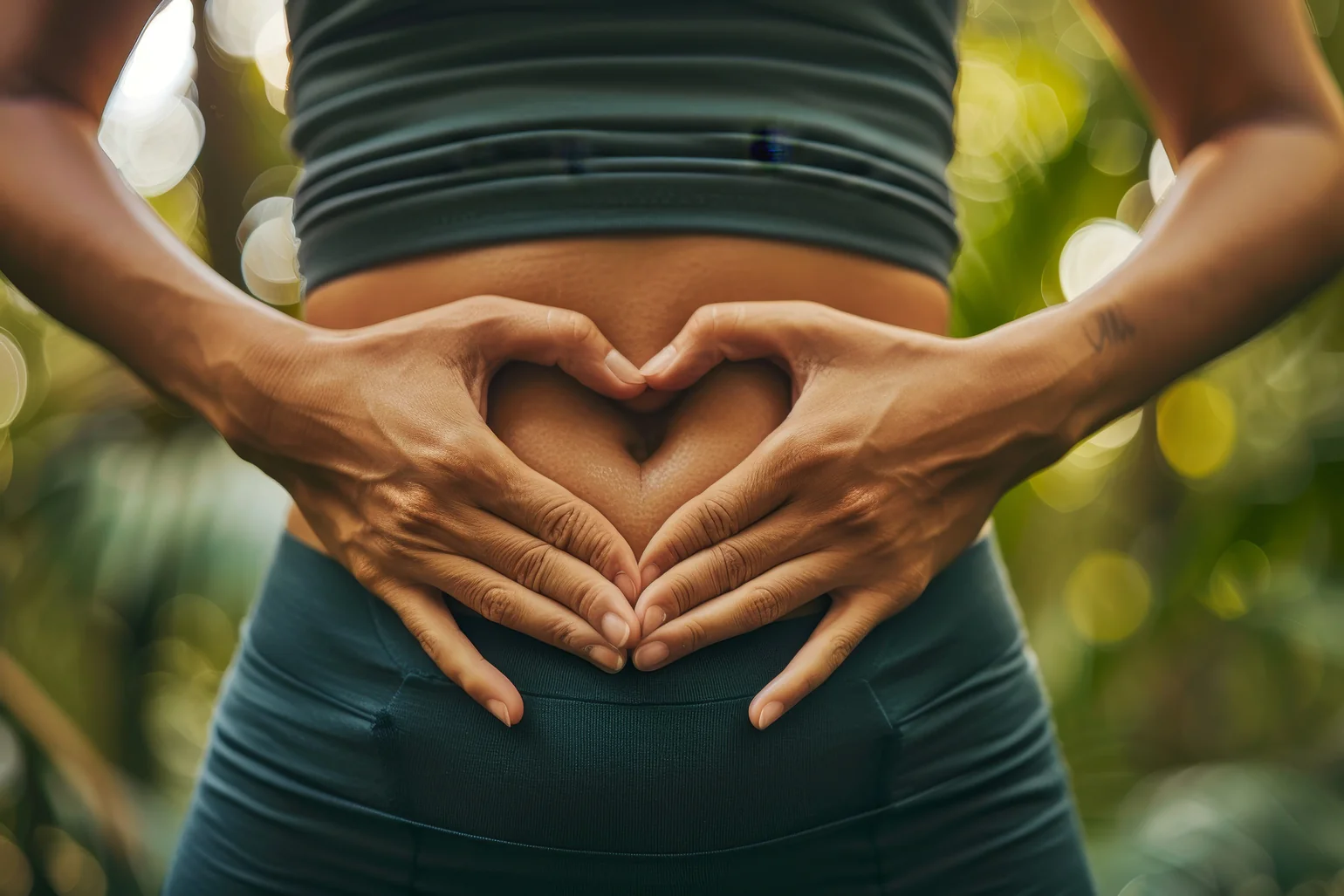 Female torso with hands placed in a heart shape over stomach. Implies she has a healthy gut.